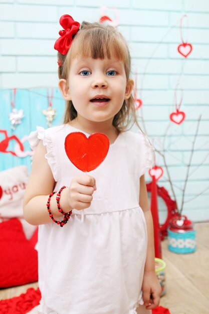 Beautiful girl holding a lollipop in the shape of heart