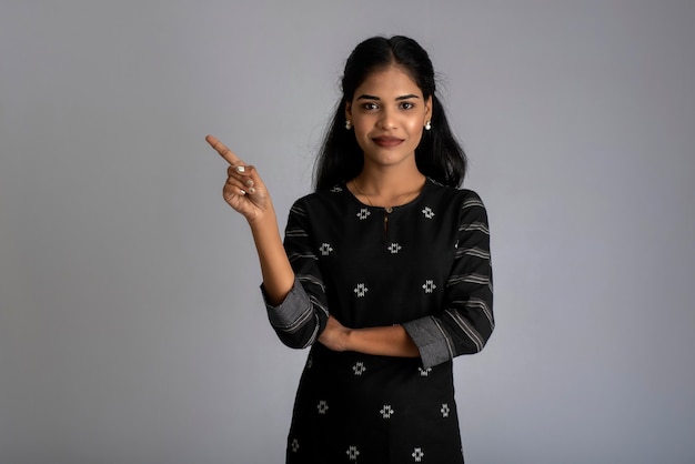 Beautiful girl holding and presenting something in the hand with a happy smiling face.