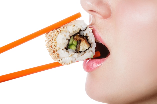 Photo beautiful girl holding sushi with a chopsticks, closeup