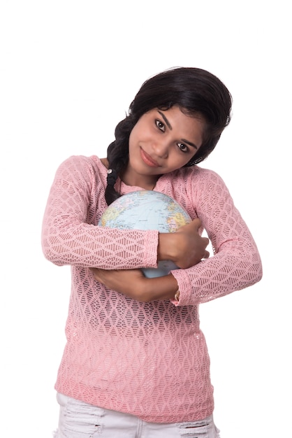 Bella ragazza che giudica un globo del mondo isolato su uno spazio bianco