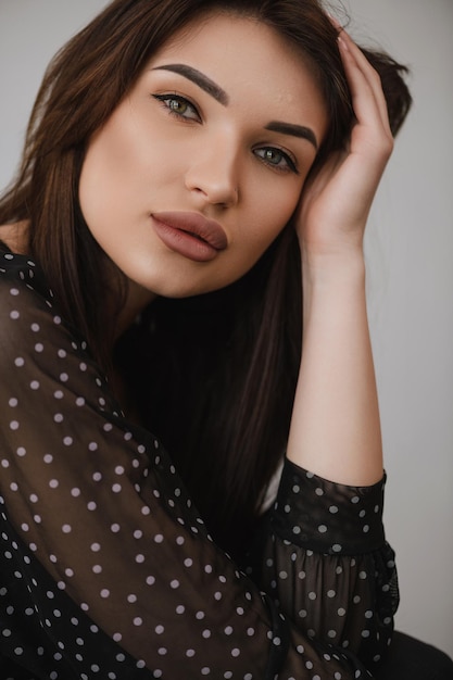 Beautiful girl holds a hand near the head on a white background