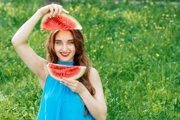 Photo beautiful girl holds two slices of watermelon