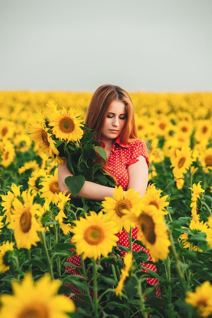 Beautiful girl in a huge yellow field of sunflowers. 