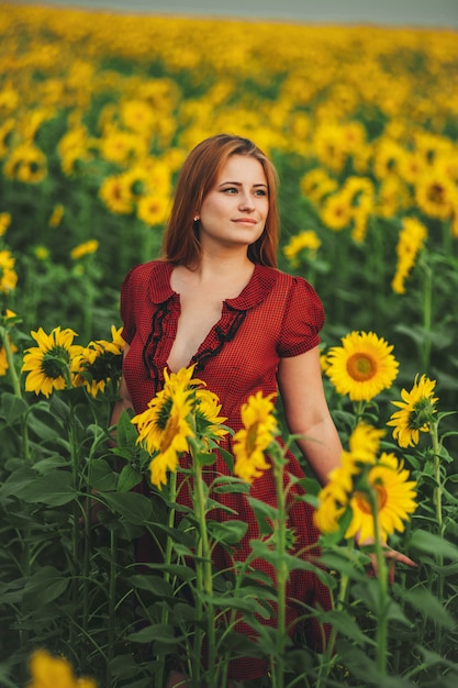 Beautiful girl in a huge yellow field of sunflowers. 