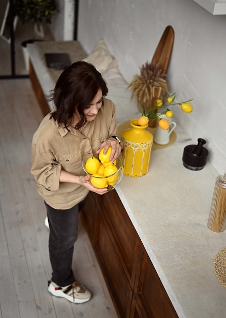 Фото Красивая девушка на бежевой кухне с желтыми лимонами в сицилийском стиле италия