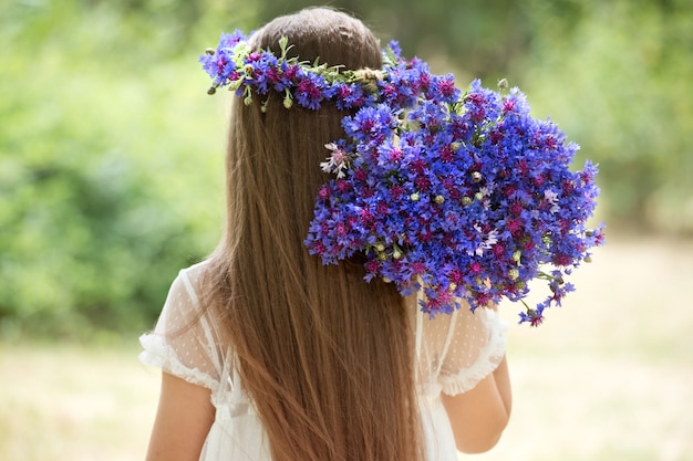 写真 ヤグルマギクの花輪とバスケットに花束を持つ美しい少女。