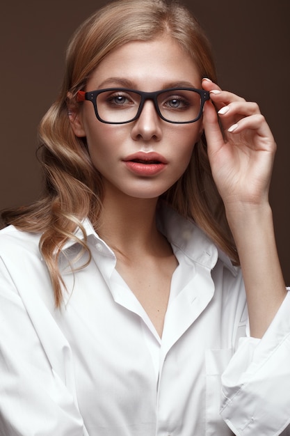 Фото Красивая девушка в стильной одежде с очками для зрения и красными сексуальными губами. красота лица. фотография сделана в студии