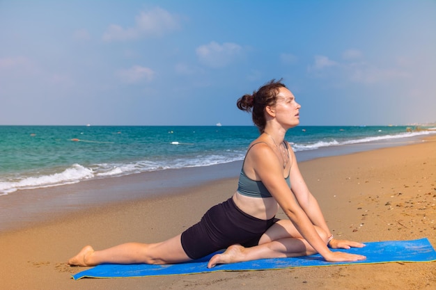 A beautiful girl is doing yoga on the beach near the sea