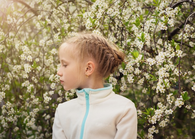 A beautiful girl is looking to the right side in the cherry orchard.