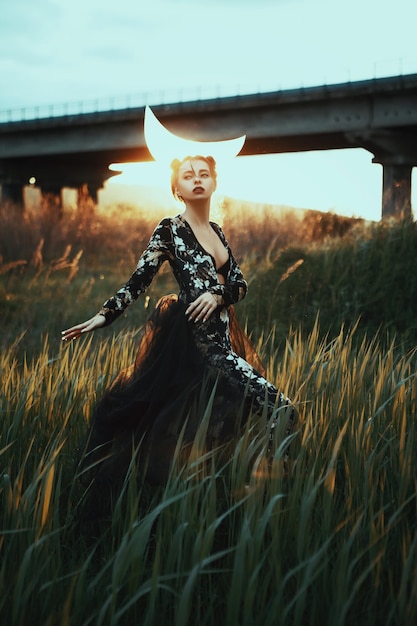 Photo beautiful girl is posing ib a nature with a moon on her head