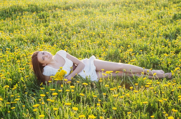 美しい少女は庭の芝生の上に横たわってリラックス