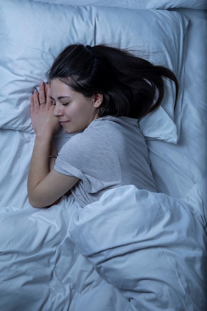 Foto una bella ragazza sta dormendo in un letto con un lenzuolo bianco