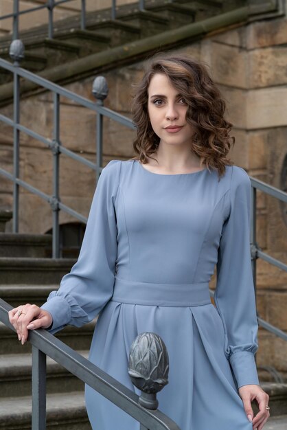 A beautiful girl is standing on the stairs in the castle Feminine tenderness and grace