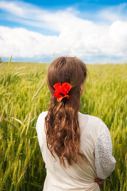 Beautiful girl is standing with her back in a white dress in a wheat field