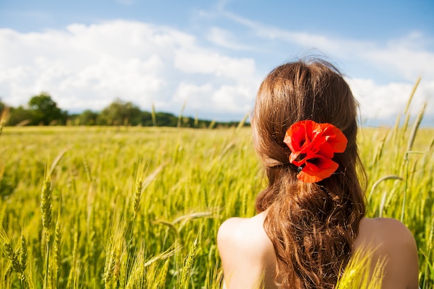 Красивая девушка стоит спиной в белом платье на пшеничном поле