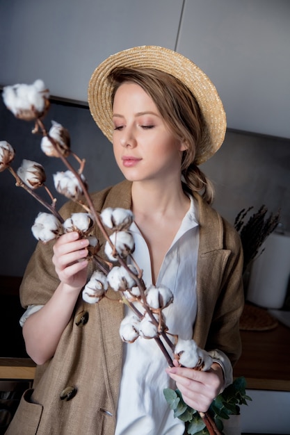 Foto bella ragazza in giacca con tote bag e pianta di cotone in una cucina a casa. concetto di sano ed ecologia dello stile di vita
