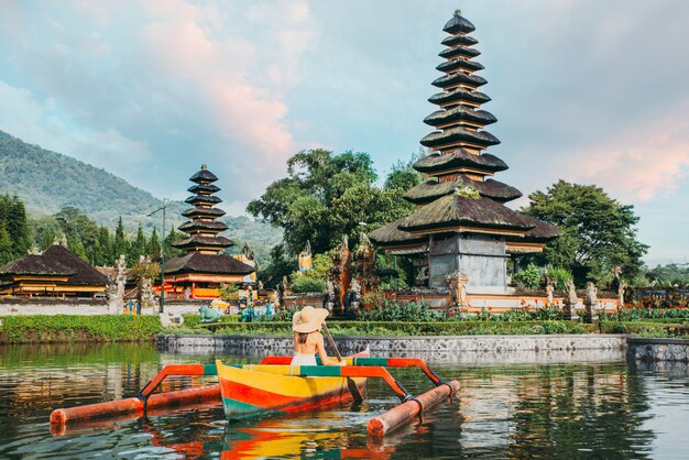 Beautiful girl kayaking on the catamaran at the ulun datu pura bratan temple, in Bali