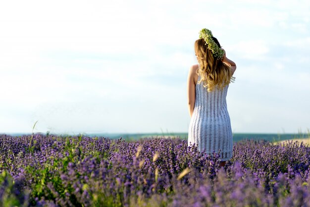 Beautiful Girl in lavender Field. Pretty woman Provence style in white dress and flowers wreath