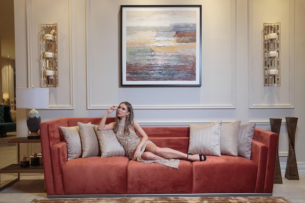 Beautiful girl laying on them red couch and looking at the camera