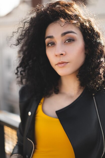 A beautiful girl in a leather jacket poses against the background of the city