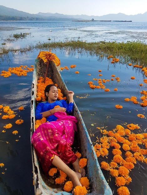 インドネシア・バリ島キンタマーニ湖のマリーゴールドとボートに横たわる美しい少女