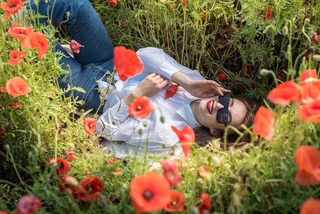 Beautiful girl lies in a red poppy field. healthy lifestyle. summer time