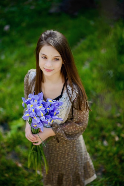 Beautiful girl in a light dress with a bouquet of spring flowers of irises