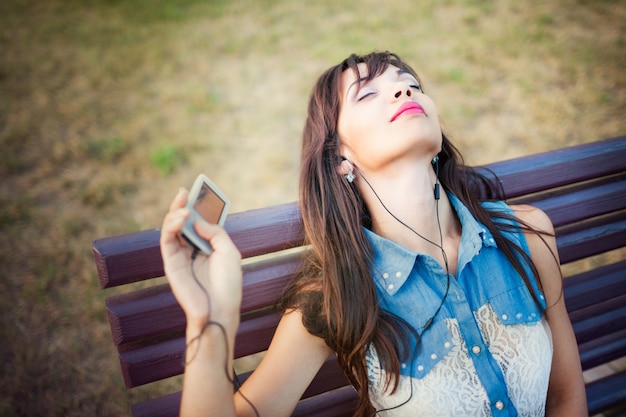 Красивая девушка слушает музыку на открытом воздухе