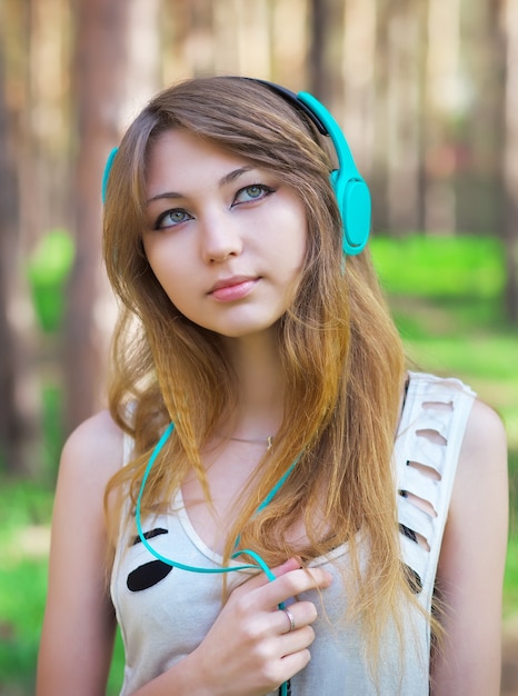 Photo beautiful girl listening to music with headphones at the park