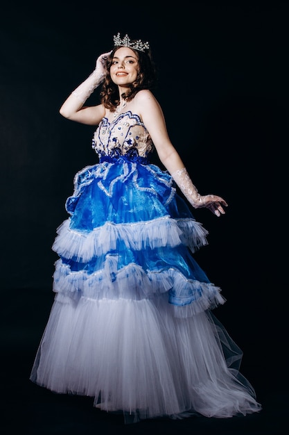 Beautiful girl in a long blue evening dress on a black background