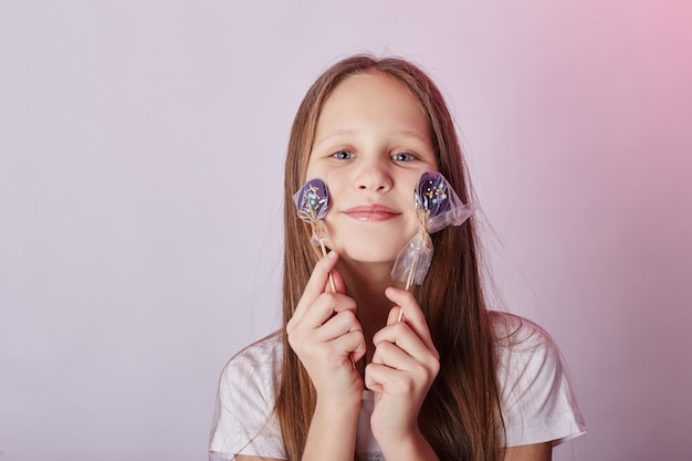 I capelli lunghi della bella ragazza mangiano il caramello della lecca-lecca