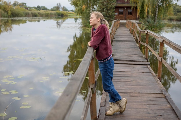 Beautiful girl look dreaming stands on a wooden bridge