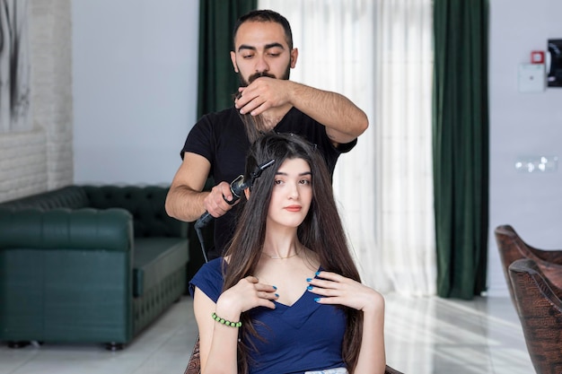 A beautiful girl looking at the camera while male Barber making her hair High quality photo