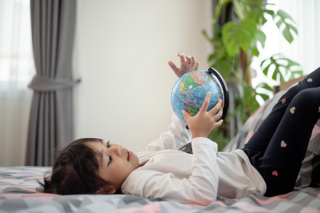 Beautiful girl looking at an earth globe and learning about geography