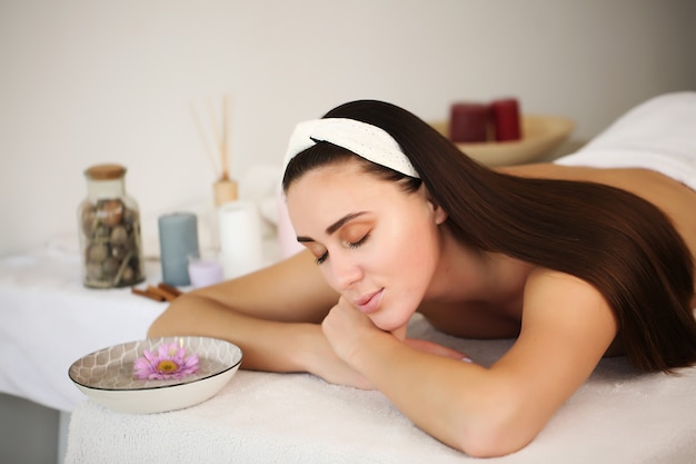 Beautiful girl lying on the table wrapped in a towel in the spa