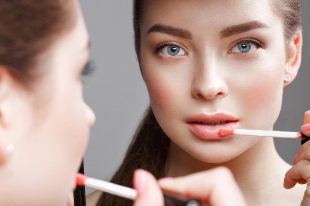 Красивая девушка делает себе макияж в зеркале Красивое лицо Фото сделано в студии