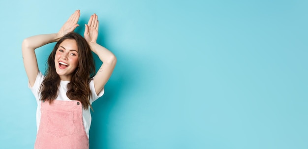 beautiful girl mimic easter bunny showing rabbit ears with hands on head and smiling lovely dancing