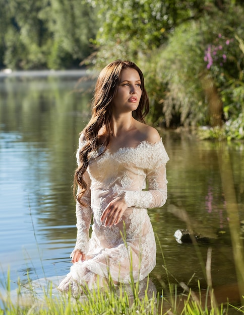 The Beautiful girl model in a dress in the water on the river