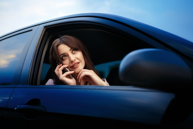 beautiful girl model sitting in the car and use the phone