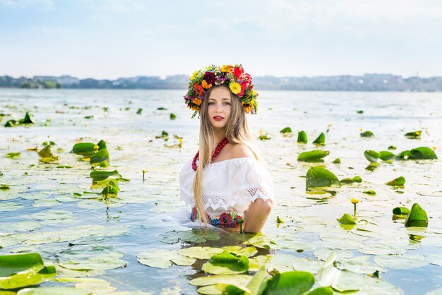 Beautiful girl in national clothes standing in lake