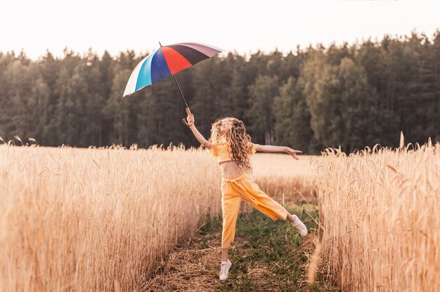 Beautiful girl in nature in the summer with a colorful umbrella