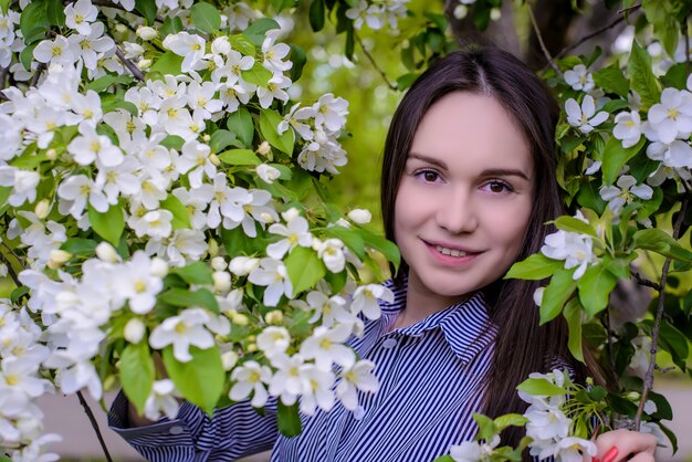 Beautiful girl near blooming apple trees in spring