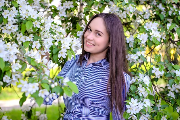 Beautiful girl near blooming apple trees in spring