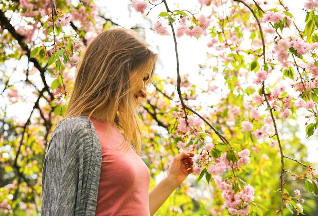 Beautiful girl near blooming tree Blossom sakura outdoors Spring mood Woman relaxing