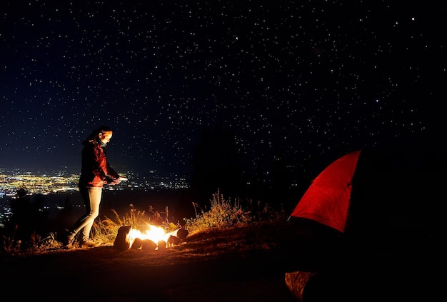 Beautiful girl near campfire at starry night