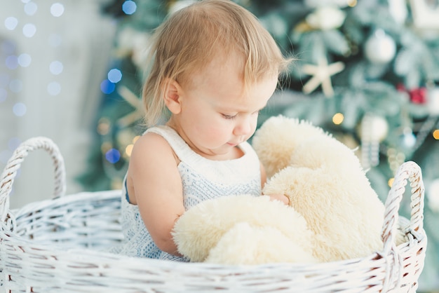 Beautiful girl near decorated Christmas tree with toy wooden rocking horse. Happy new year. Portrait little girl.