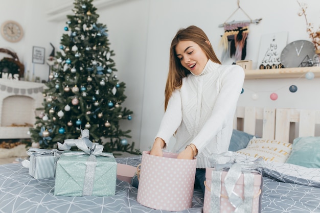 A beautiful girl opens Christmas gifts.