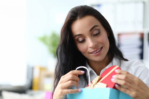 Beautiful girl opens package with gift form heart