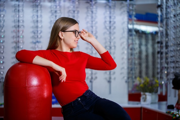 Beautiful girl in an ophthalmology center picks up glasses for vision correction