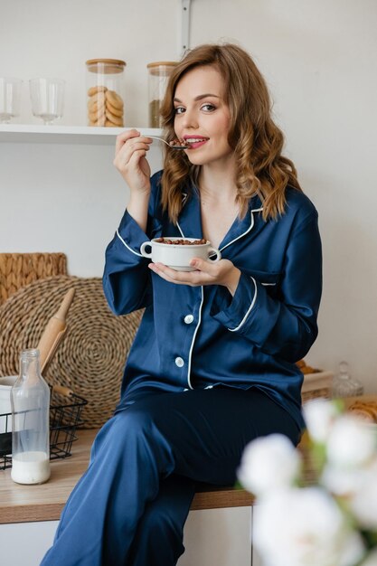 Photo beautiful girl in pajamas eating cereal in the kitchen